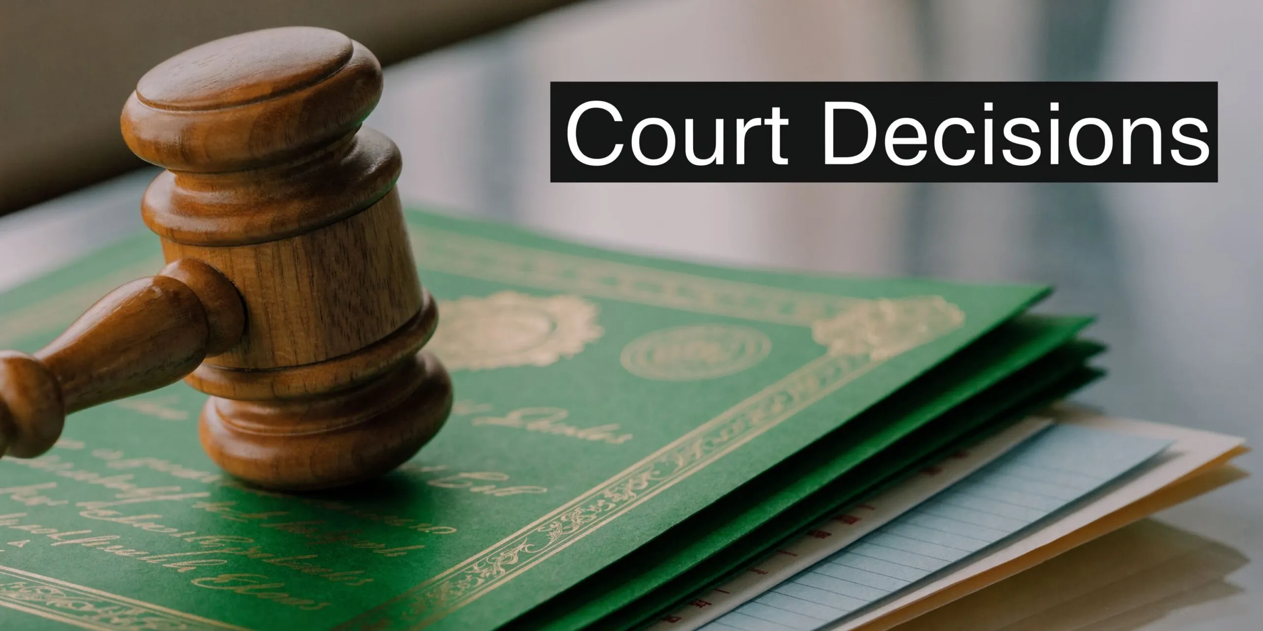 A wooden judge's gavel resting on top of a stack of important legal documents and certificates.