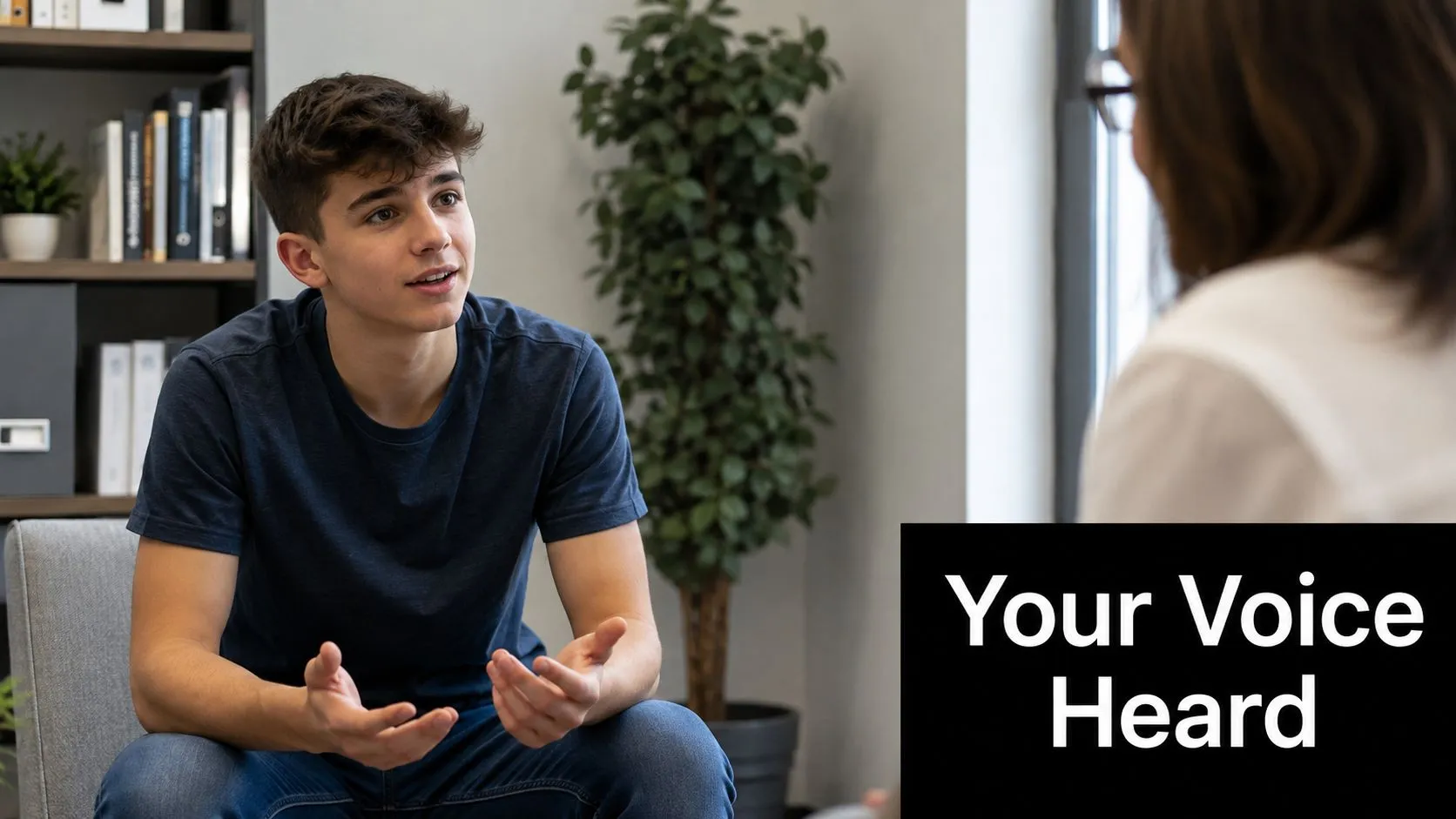 A young man sitting in an office chair speaking to a professional in a therapeutic setting.